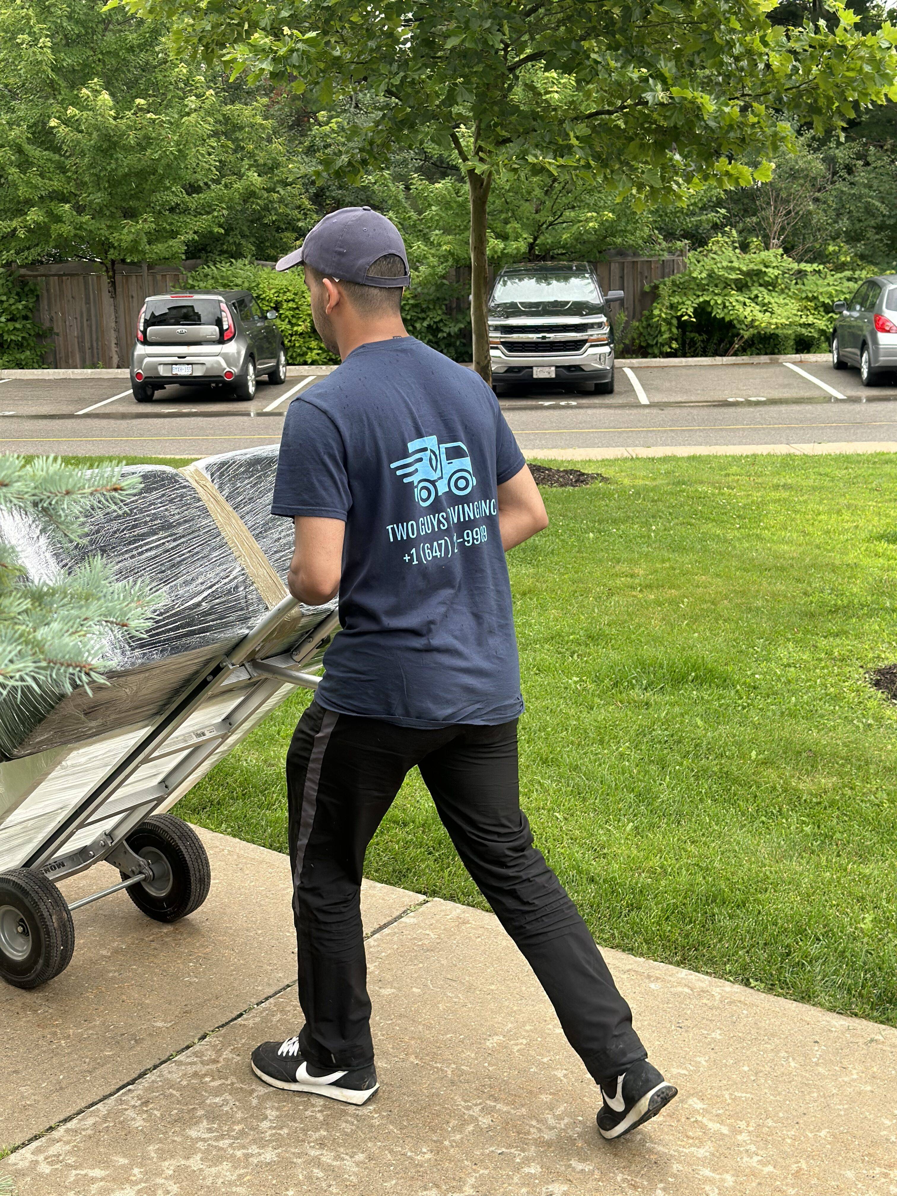 A mover from Two Guys Moving Inc moving furniture on a dolly