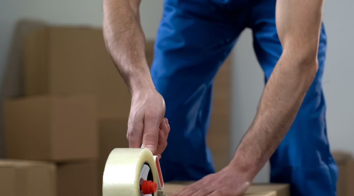 A man closing a box with tape